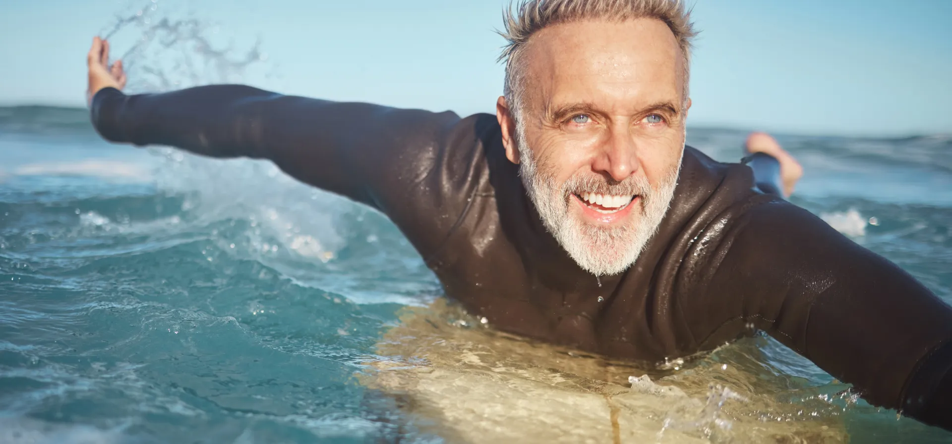 A smiling surfer paddling out on the ocean